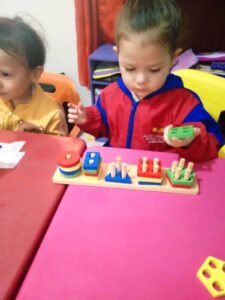 Dos niños jugando con bloques de madera Montessori en una mesa.