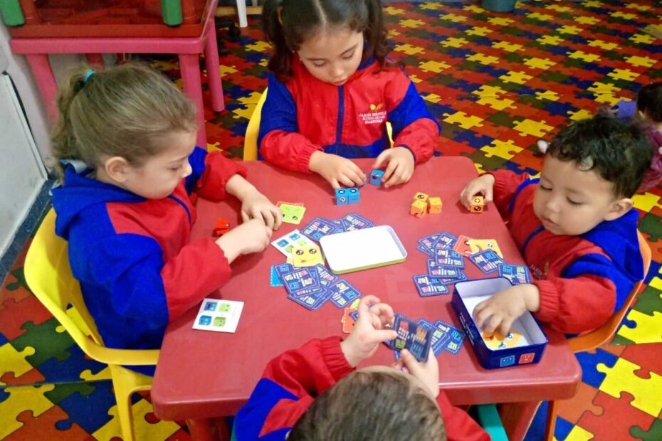 Niños en un aula Montessori jugando con bloques de colores y tarjetas, fomentando su aprendizaje autónomo y habilidades sociales.