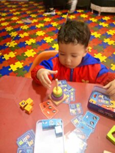 Niño pequeño jugando con un juguete apilable y bloques en un aula Montessori, promoviendo su aprendizaje y habilidades motoras.