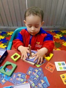 Niño pequeño jugando con un juguete apilable en un aula Montessori, promoviendo su aprendizaje y habilidades cognitivas.