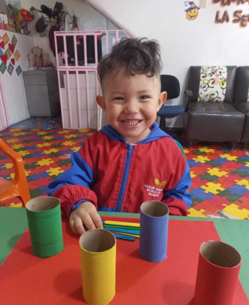 Estudiante Montessori trabajando con cilindros de colores y palitos de clasificación en ambiente preparado Montessori en bogota