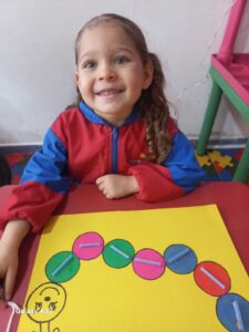 Estudiante con uniforme del jardín Montessori trabajando con material didáctico de círculos de colores el montessori en bogota