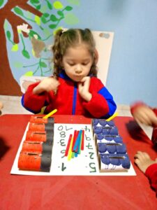 Actividad Montessori de motricidad fina en Jardín Infantil El Mundo de las Mariposas, donde una estudiante desarrolla habilidades matemáticas y coordinación mediante materiales didácticos